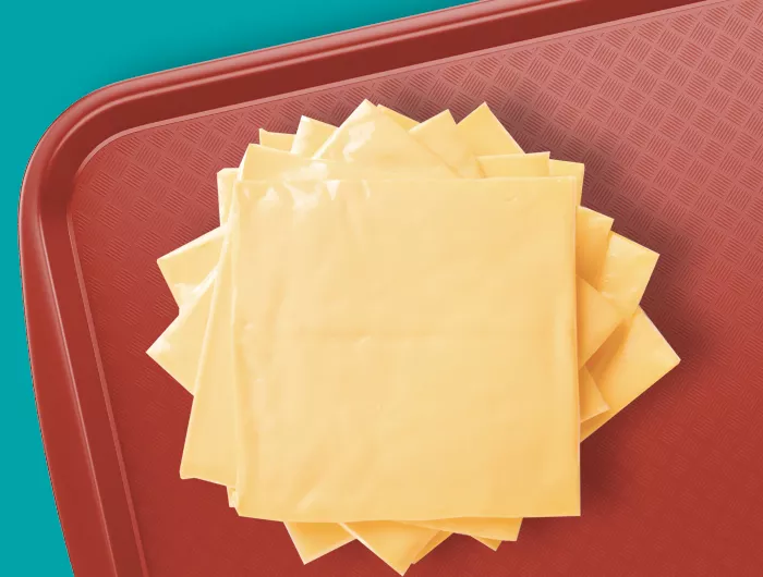 A stack of cheese slices on a cafeteria tray.