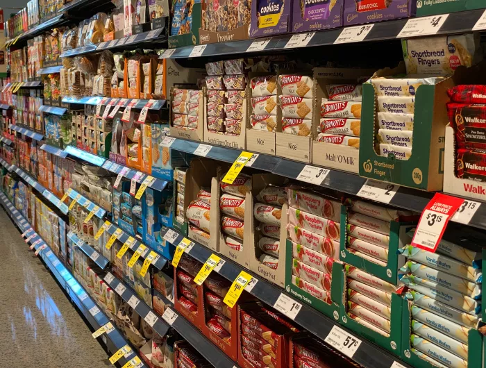 A supermarket shelf filled with pre-packaged products that lack front of package labeling