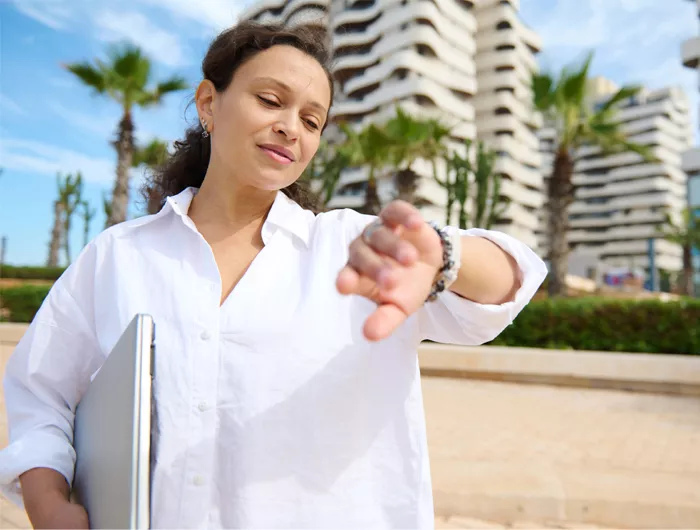 woman standing outside and looking at her watch