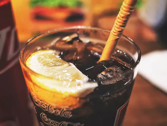 A glass of cola with ice and an orange wedge