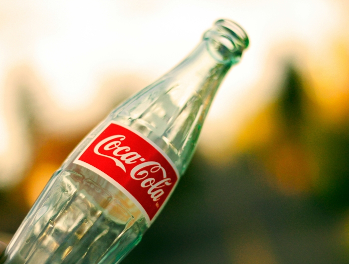 An empty bottle of Colca-Cola with a colorful blurred background