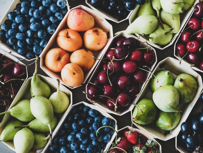 Seasonal produce - Flat-lay of ripe strawberries, cherries, grapes, blueberries, pears, apricots, figs in wooden eco-friendly boxes