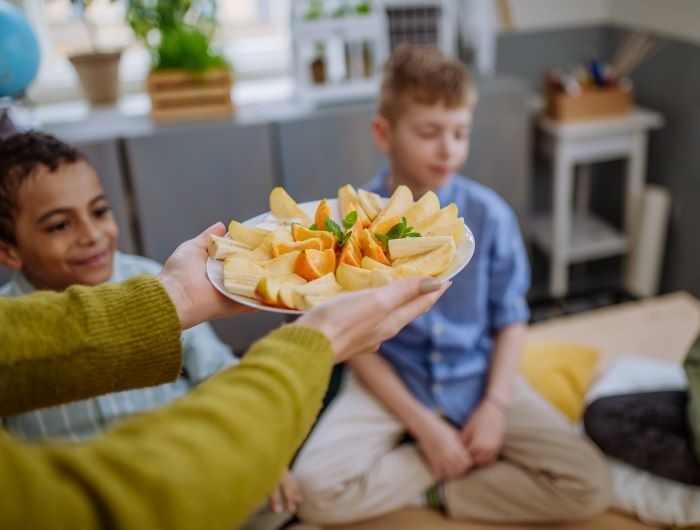 An instructor presents a healthy snack plate of fruit for students at an afterschool meeting