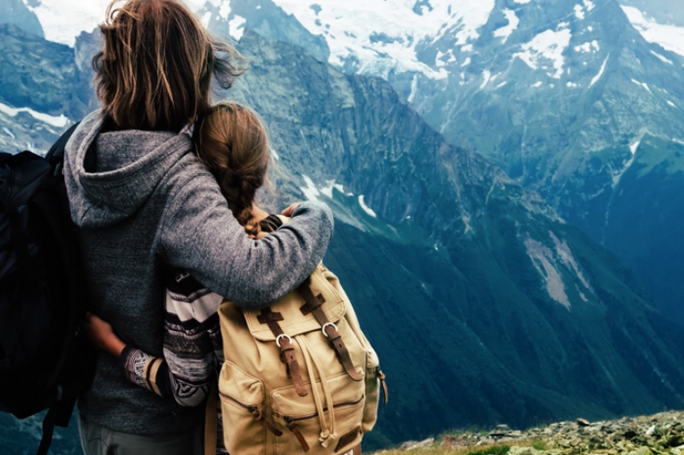 woman and young girl standing together looking over snow capped mountains