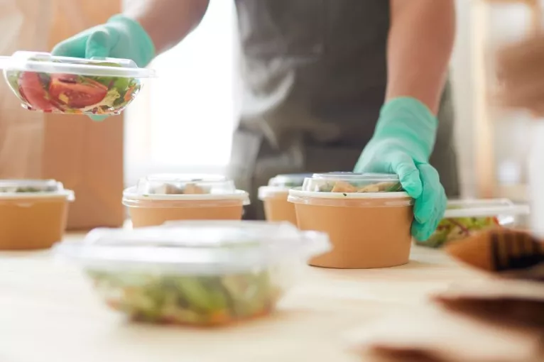 Close up of worker wearing protective gloves while packaging food 