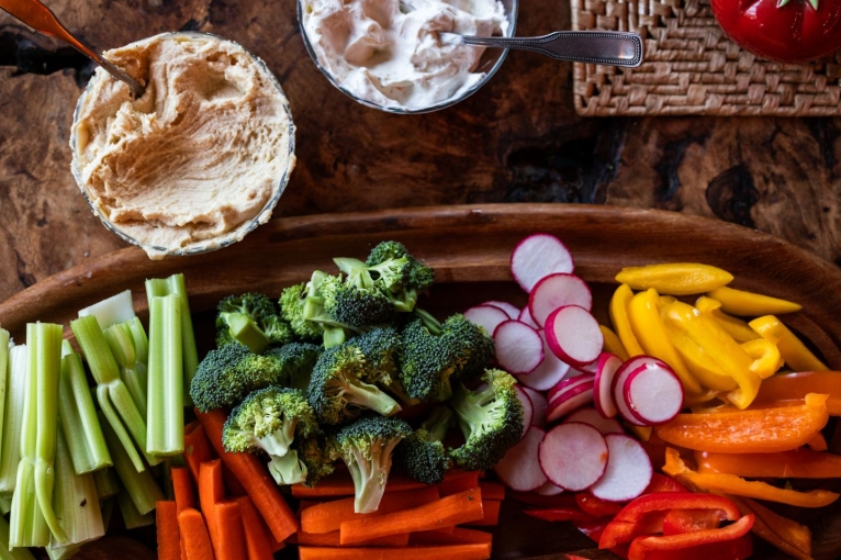 Vegetables with hummus and other dips. Celery, broccoli, carrots, radishes, bell peppers on a platter