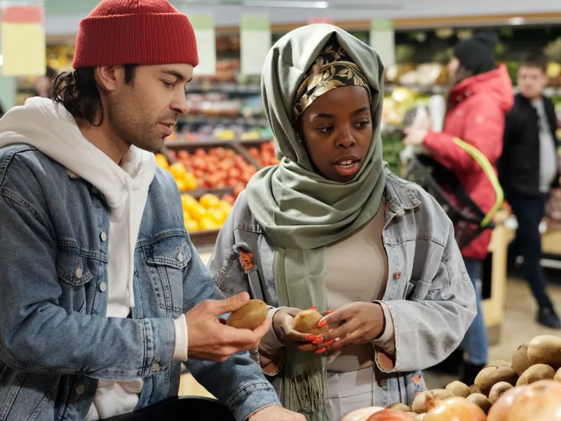 A young man and woman shopping in a grocery store produce aisle