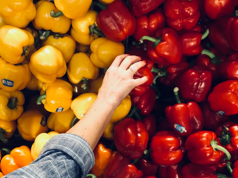 A woman selecting a red bell pepper