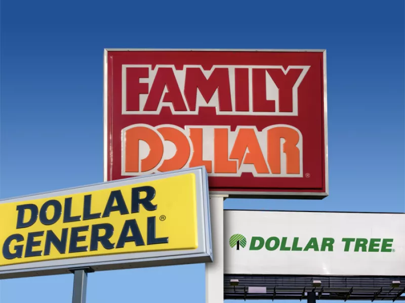 Signs for Dollar General, Family Dollar, and Dollar Tree with a blue sky in the background