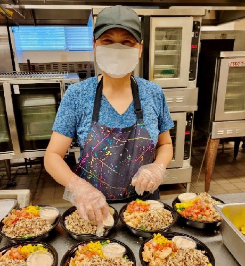 A staff member at MCPS prepares lunch portions