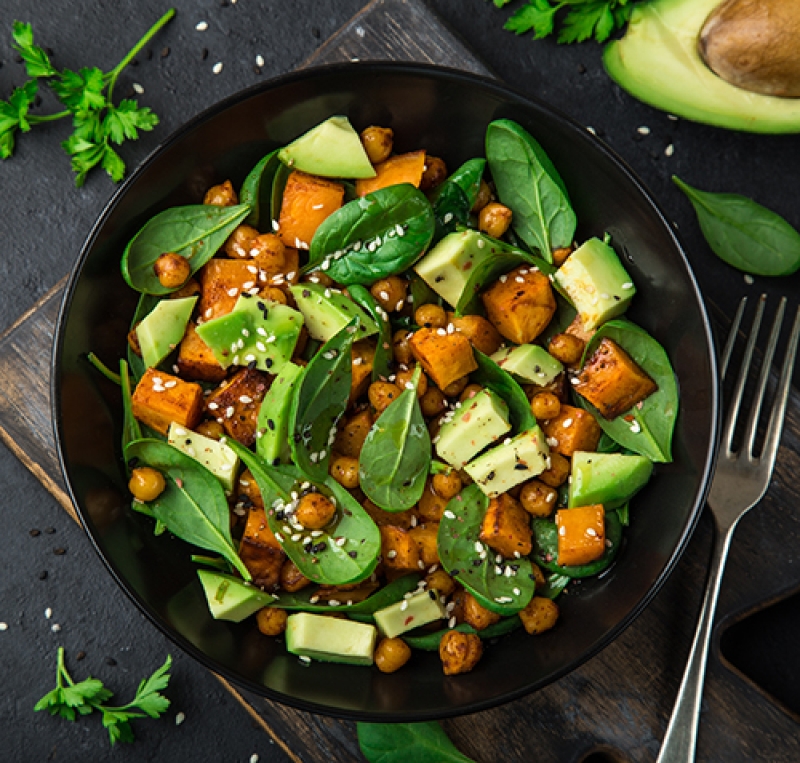 Bowl of spinach, chopped avocado, chopped sweet potato