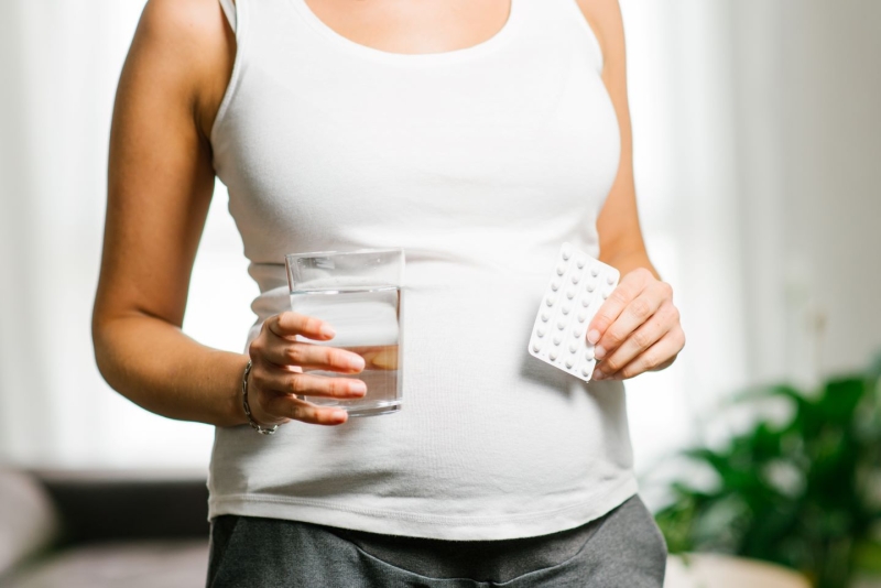 Pregnant woman holding folic acid supplement blister
