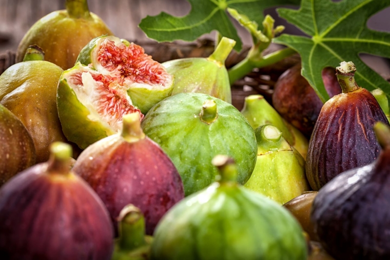 A variety of fresh figs, including red and honey fleshed types, on a table