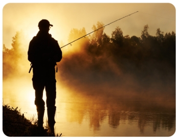 silhouette of man standing next to a steamy lake while fishing