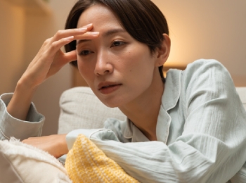 woman sitting on couch holding her head